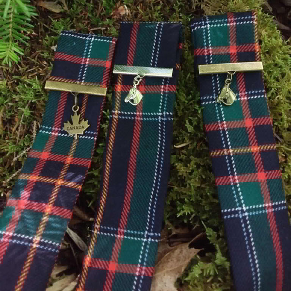 Three RCMP Tartan Bookmarks with metal clasps on a green leafy background