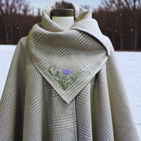 Plaid cape with embroidered design in a snowy landscape