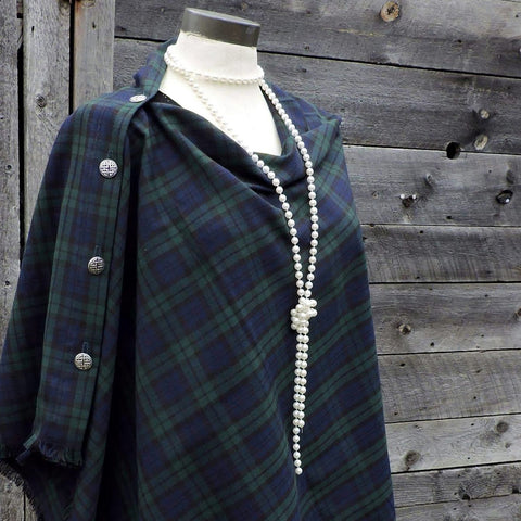A black watch tartan button shawl with fringed hemline displayed on a mannequin.